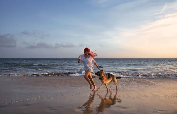日落时分 红头发的女人和她的德国牧羊犬在海滩上奔跑 带着健康的生活方式或度假观念 在湿沙上倒影 暑假期间的友谊 乐趣和享受 — 图库照片