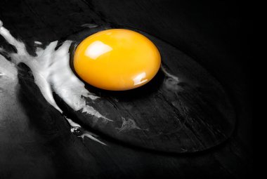 Düz siyah yüzey üzerinde çiğ yumurta