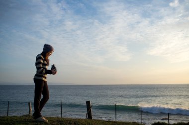 Genç kadın deniz fotoğraflarını deniz kenarında