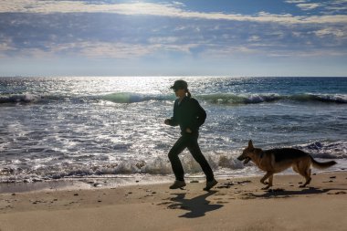 Onun köpeği ile deniz kenarında kadın Jogging