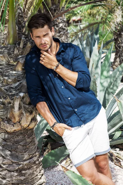 Modelo guapo posando bajo la palmera — Foto de Stock