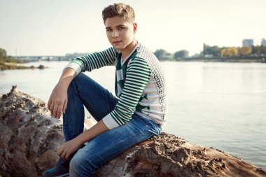 Yakışıklı çocuk düşmüş ağaç üzerinde oturan 