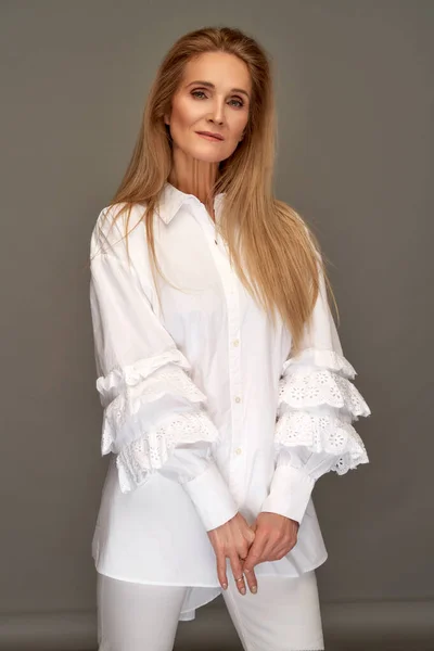 成熟的女模特 长发直发 灰色工作室背景下穿着白色时髦衬衫 — 图库照片