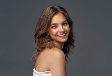 Gri arka planda izole edilmiş neşeli genç kadın.