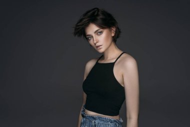 Kısa saçlı ve kameraya bakan esmer bir kadının stüdyo çekimi.