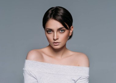 Kısa saçlı, gri arka planda izole genç, şehvetli esmer kadının stüdyo çekimi.