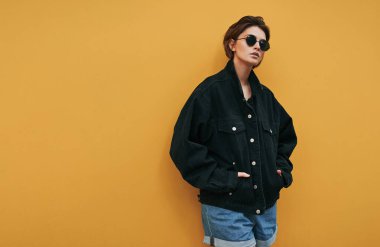 Güneş gözlüklü ve siyah ceketli genç bir kadının klasik fotoğrafı. 