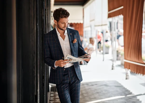 Handsome man in checked suit reading newspaper on the street