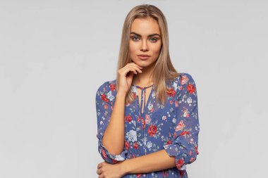 Gri arka planda izole edilmiş sevimli sarışın modelin portresi