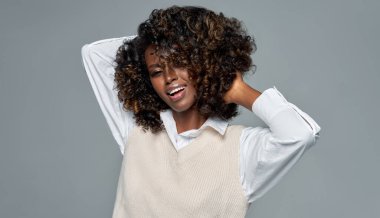 Gri arka planda afro saç stili olan neşeli Afrikalı Amerikalı kadın. 