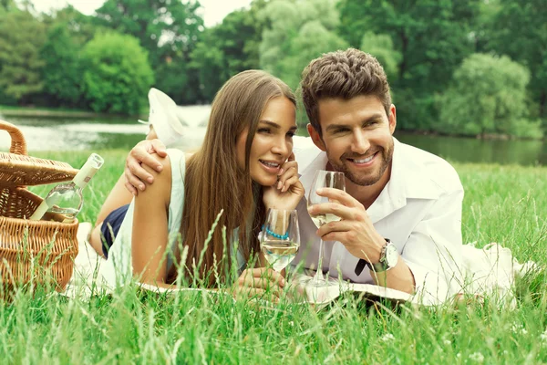 Coppia felice su picnic bere vino bianco — Foto Stock