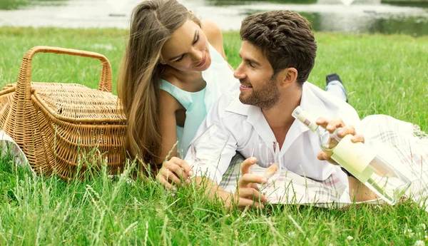 Atractiva pareja en picnic bebiendo vino blanco — Foto de Stock