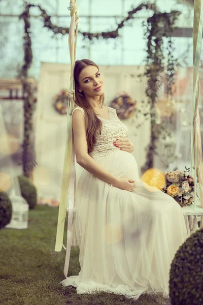 Těhotná žena sedí na houpačce — Stock fotografie
