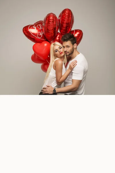 Attractive couple with red balloons — Stock fotografie