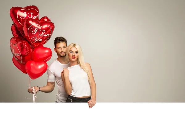 Attractive couple with red balloons — Stock Photo, Image