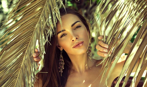 Beautiful woman between palm leaves — Stock Photo, Image