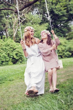 Anne ve kızı bir salıncak üzerinde oturan