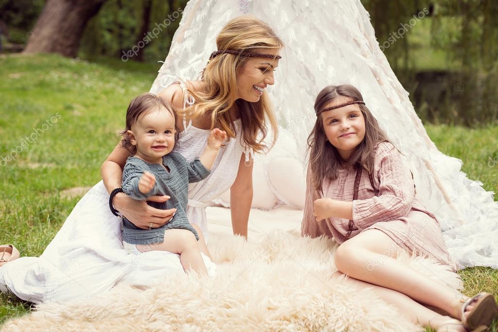 Mother and children are sitting in a tent teepee and having fun