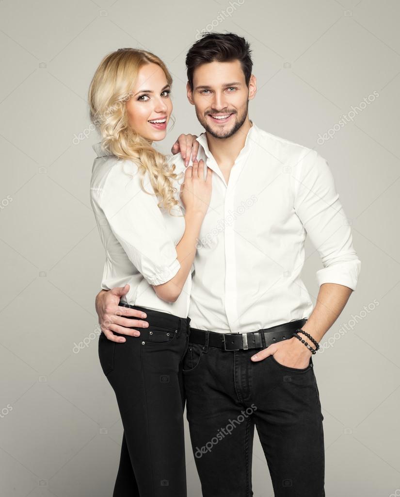 Fashionable couple in white shirts, posing on grey background