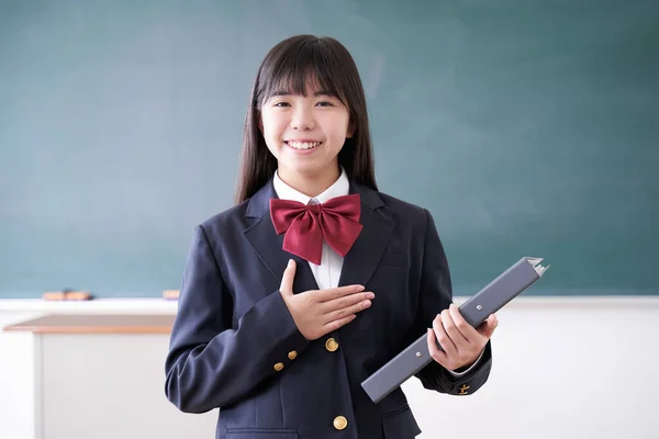 A Japanese junior high school girl greets students in the classroom with a smile