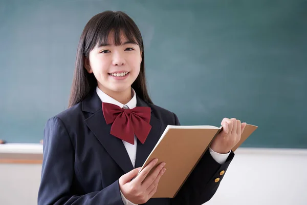 A Japanese junior high school girl opens her notebook in the classroom