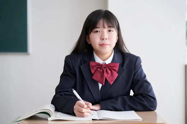 A Japanese junior high school girl studies in the classroom with a straight face