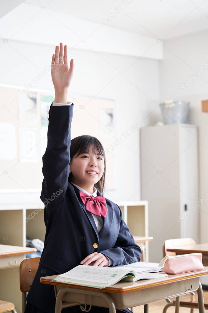 A Japanese junior high school girl raises her hand in the classroom