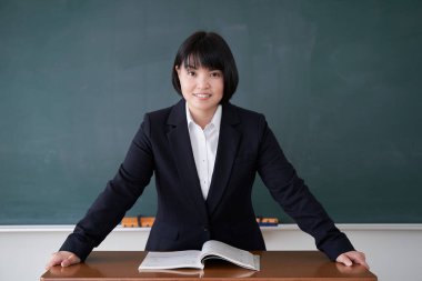 Sınıfında bir Japon kadın öğretmen tahtanın önünde duruyor.