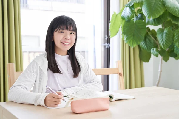 Japanese junior high school girls doing their homework in the living room