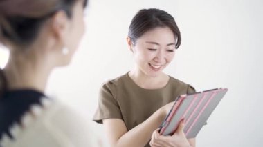 Japon estetisyen bir tablet kullanarak güzellik salonunda danışmanlık yapıyor.