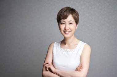 Kollarını kavuşturup kameraya bakan orta yaşlı bir Japon kadın.