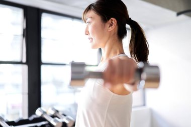 Asian woman doing dumbbell training indoors