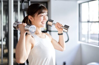 Asian woman doing shoulder press in training gym