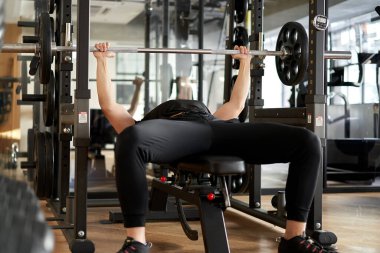 Spor salonunda göğüs presi yapan Asyalı bir adam.