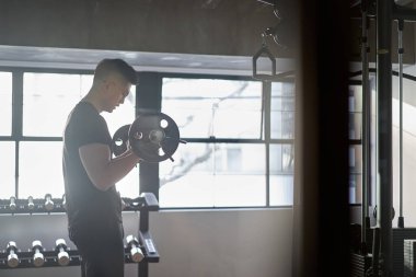 Spor salonunda halter kıvıran Asyalı bir adam.