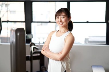 Antrenman salonunda gülümseyen Asyalı bir bayan antrenör.