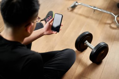 Asyalı adam akıllı telefondan eğitim uygulamasını izliyor.