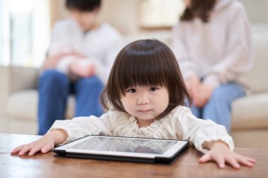 Asyalı bir kız tek başına tablete bakıyor.