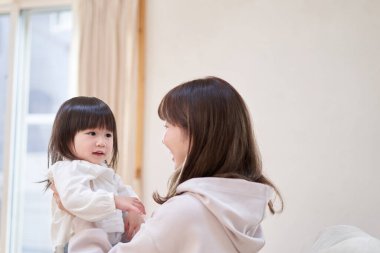 Asyalı anne kızını kucaklıyor.