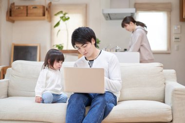 Annesi ev işlerini yaparken Asyalı baba çocuğuna bakıyor.