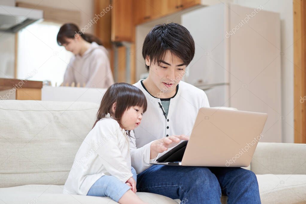 Asian dad taking care of his child while mom is doing household chores