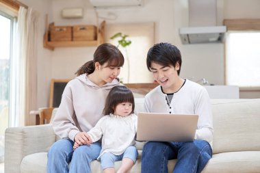 Asyalı bir aile oturma odasındaki bilgisayara bakıyor.