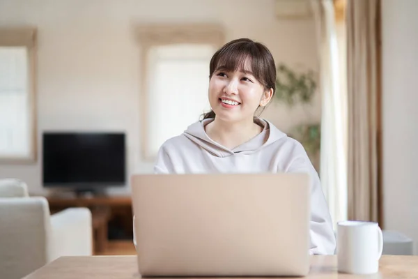 Asian woman operating a computer with a smile in the living room