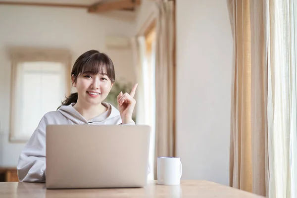 Asian woman operating a computer with a smile in the living room