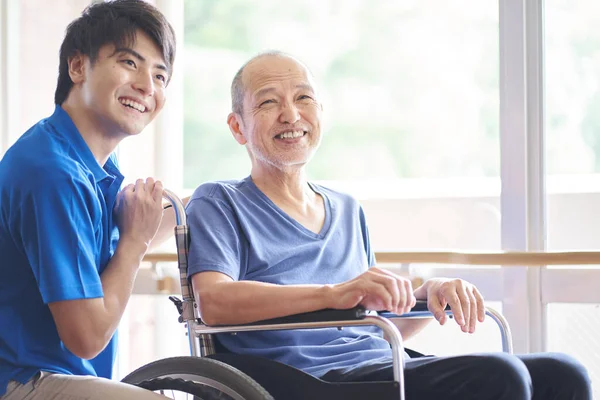 高齢者や介護者に乗る車椅子 — ストック写真