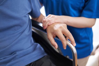 Tekerlekli sandalyedeki yaşlı insanların ve bakıcıların elleri