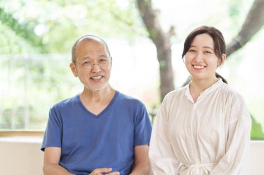 Asyalı aileler ve çocuklar gülümseyerek oturuyor.