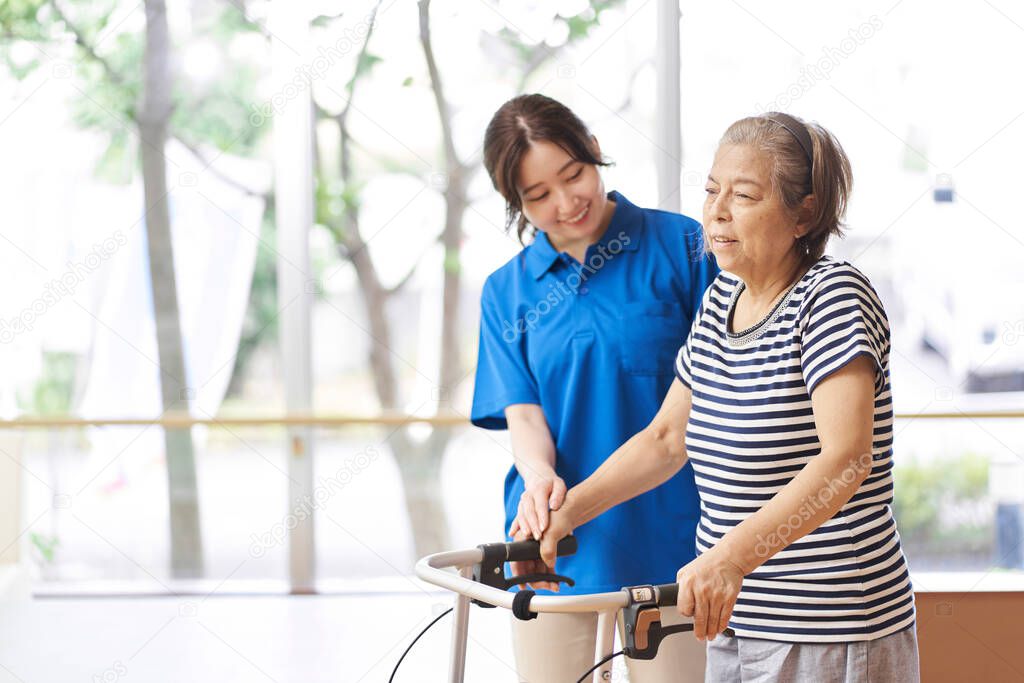 A caregiver who assists the elderly walking with a walker
