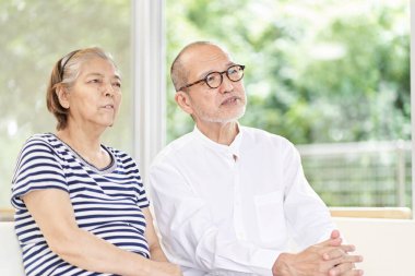 Kanepede oturan ve ciddi bir konuşma yapan yaşlı çift.