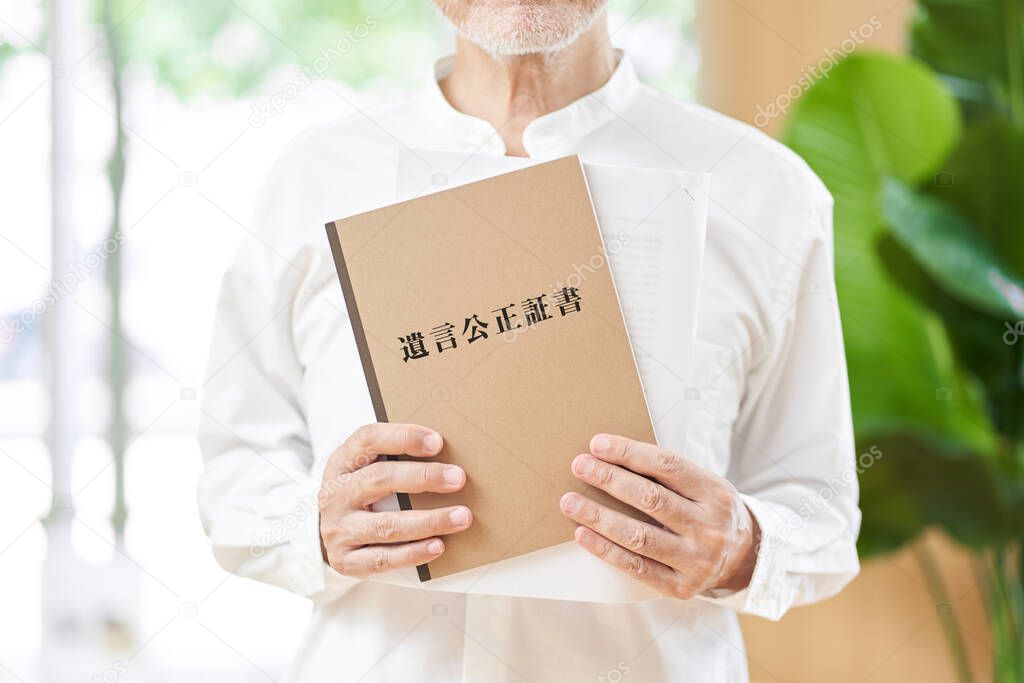Hands of an elderly person with a document written as a notarial act in Japanese